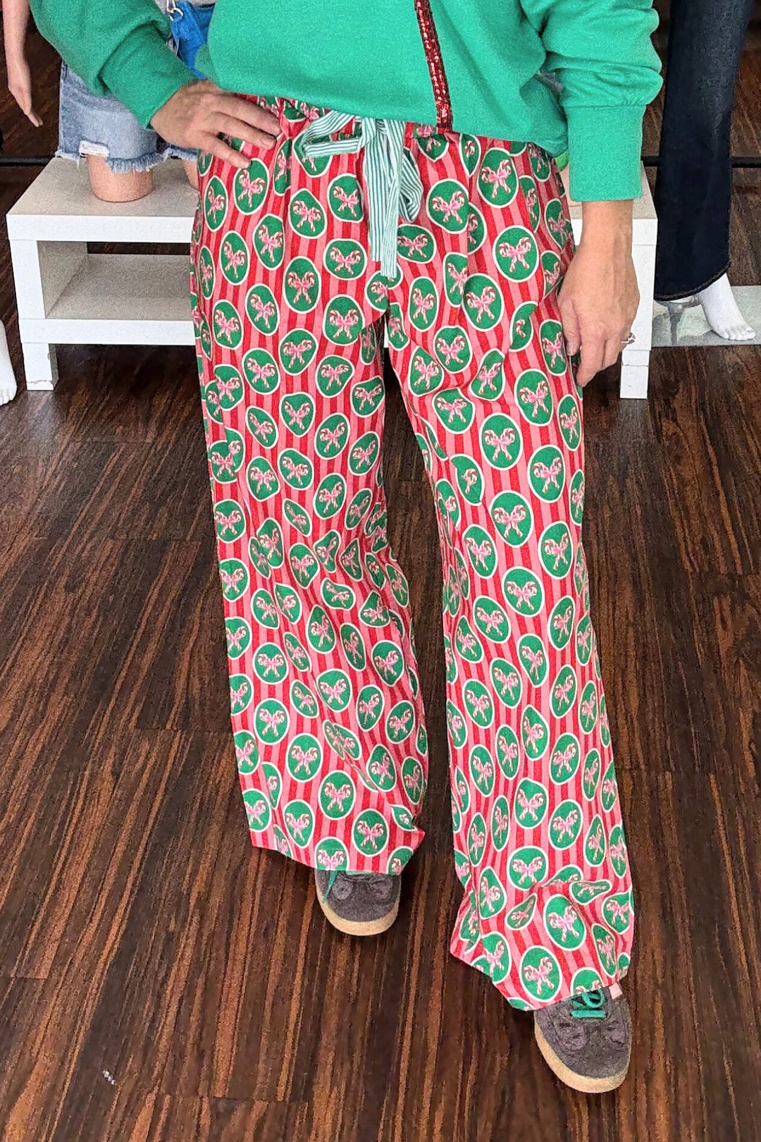 Experience cozy comfort with these Christmas Print Cotton Pajama Pants featuring a festive red and pink stripe complemented by a candy cane detail. The green and cream striped waist tie adds a stylish touch and allows for an adjustable fit. 