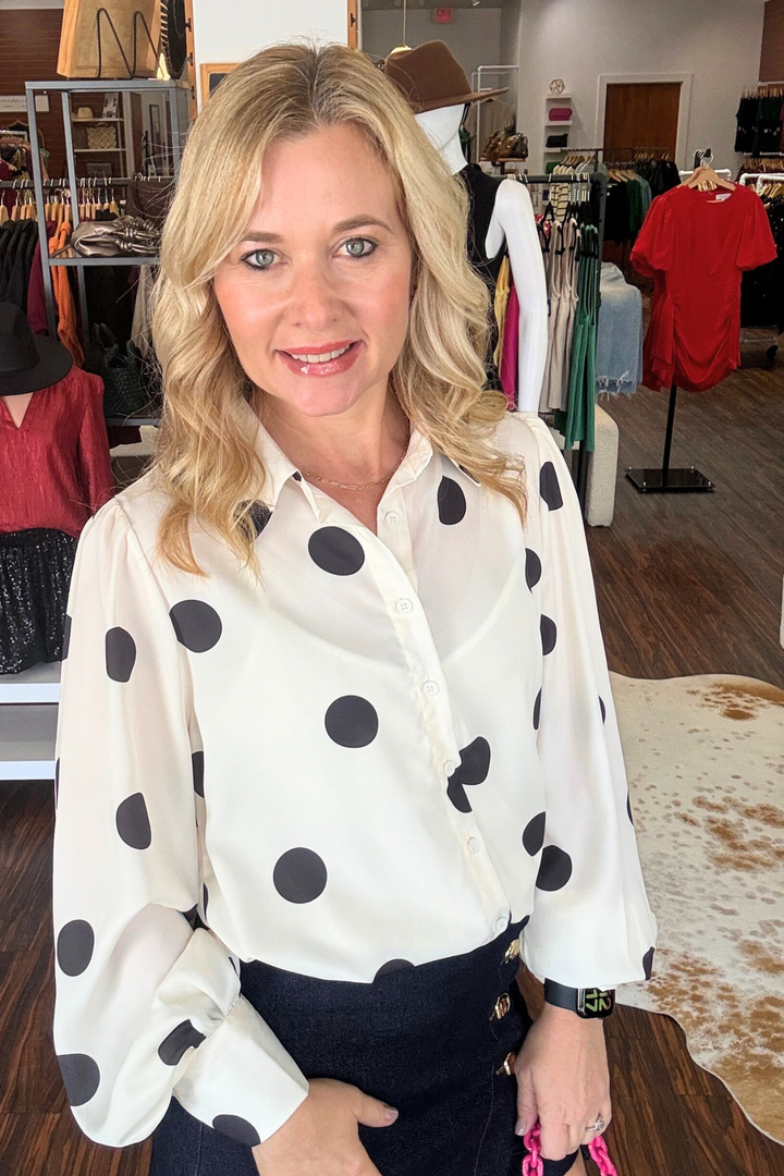 Cream Top with Black Polka Dots

Effortless layering meets timeless style with this cream button-down top featuring delicate black polka dots. The built-in cami with adjustable straps provides coverage and versatility, while the classic collar and sleeve button details add refined sophistication. Perfect for dressing up or down, this sheer piece transitions seamlessly from office to weekend wear. Model is wearing size small.&nbsp;

Material: 100% Polyester