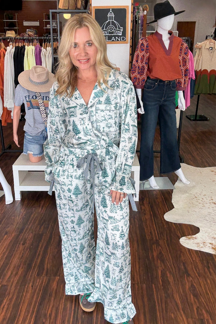 Featuring a long sleeve button-down top and matching pants, both adorned with delicate ruffle trim and complemented by gingham ties at the waist and wrists, this set blends festive charm with cozy comfort.