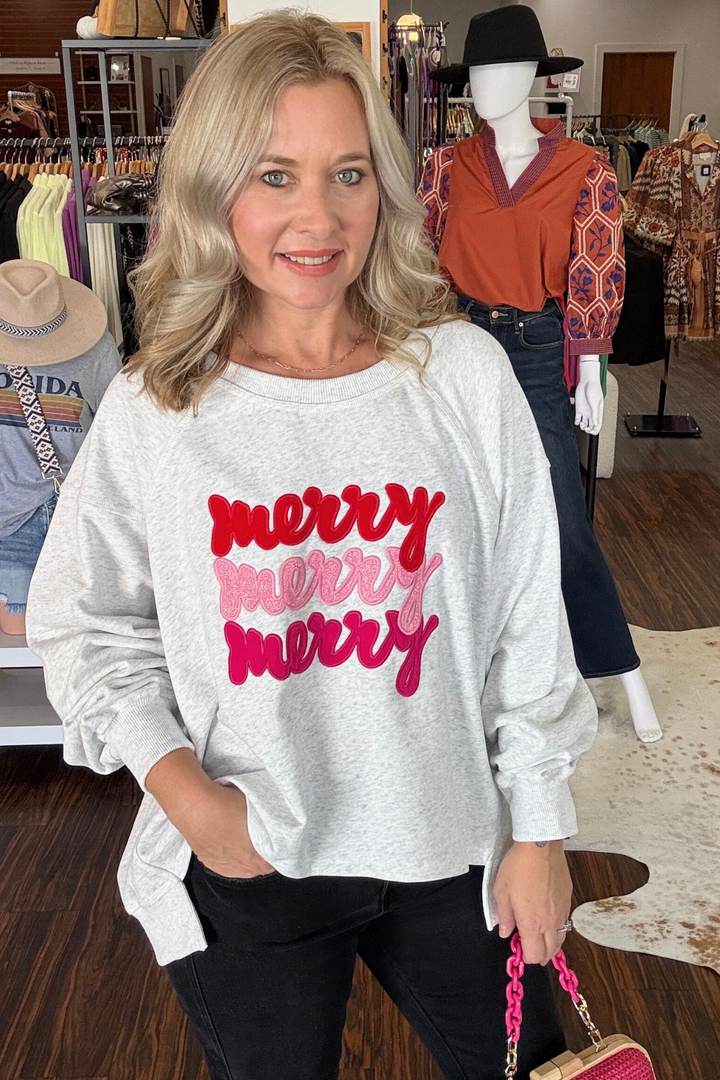 
This modern grey sweatshirt features a stylish high-low hem for a contemporary silhouette. The front is embroidered with the cheerful "Merry, Merry, Merry" phrase, adding a festive, touch. Crafted for comfortable everyday wear, it pairs effortlessly with casual or layered outfits. 