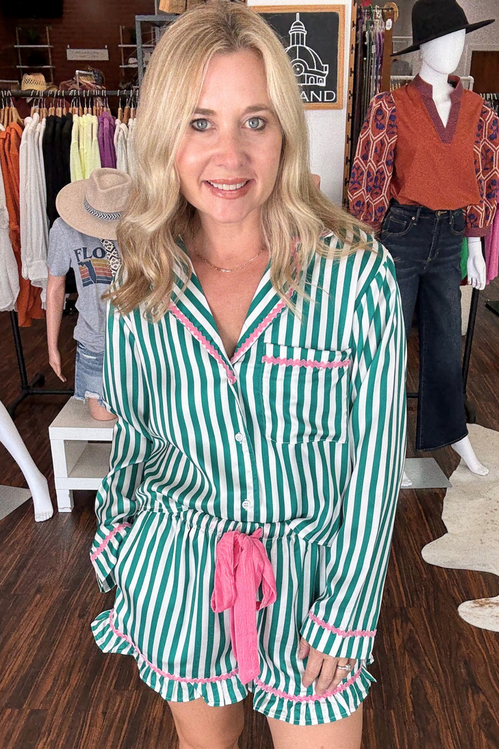 Kelly Green and Pink Satin Holiday Pajama Set features a long-sleeve, green and white striped top adorned with "Merry and Bright" across the shoulders. It pairs perfectly with matching shorts that showcase a pink tie-waist and delicate pink ric-rac trim for a fresh, festive look.