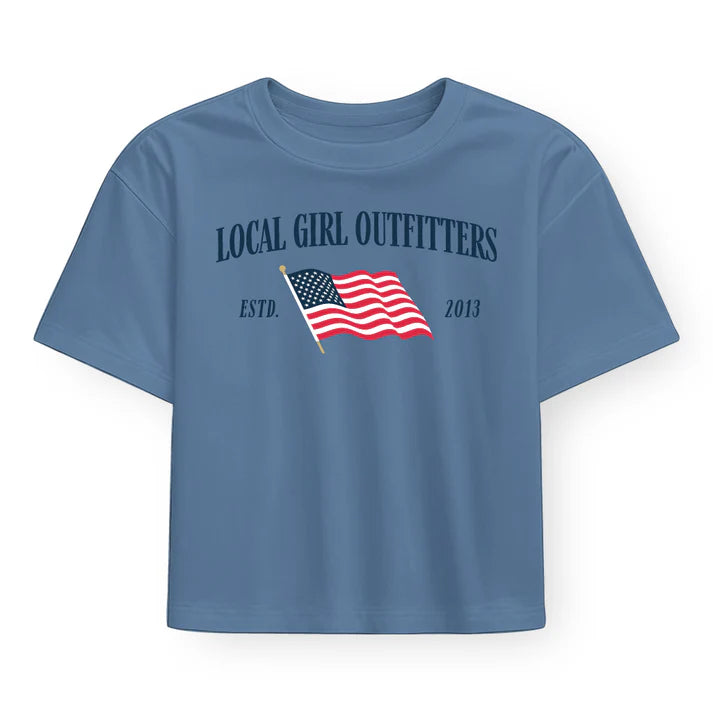 Celebrate your local pride with this slate blue cropped tee featuring a bold American flag graphic on the front. The perfect blend of patriotic style and contemporary fit, this tee works beautifully with high-waisted jeans, skirts, or layered under jackets. Soft, comfortable fabric makes it ideal for casual outings, weekend adventures, or showing your stars-and-stripes spirit year-round.