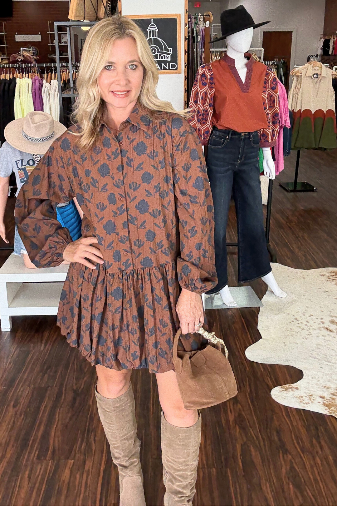 Long sleeve mini dress features a navy floral print on a warm brown background. The drop waist and button-down front create a flattering silhouette, while the bubble hem finishes the look. 