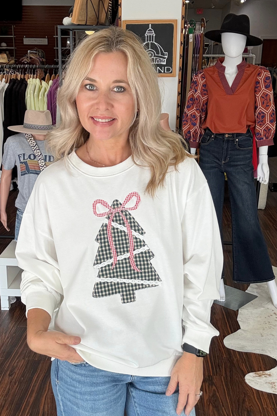 This white oversized sweatshirt features a stylish plaid patchwork Christmas tree accented with a red plaid bow, offering a festive yet modern look. Its relaxed fit ensures comfort while the unique design adds a cozy holiday touch to your casual wardrobe. 