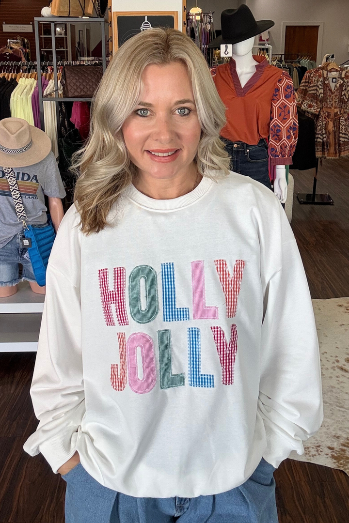 This white sweatshirt features a vibrant patchwork design spelling out "Holly Jolly" across the front, adding a festive and contemporary touch to your holiday wardrobe. Crafted for comfort and style, it pairs effortlessly with casual outfits while spreading cheerful seasonal vibes.