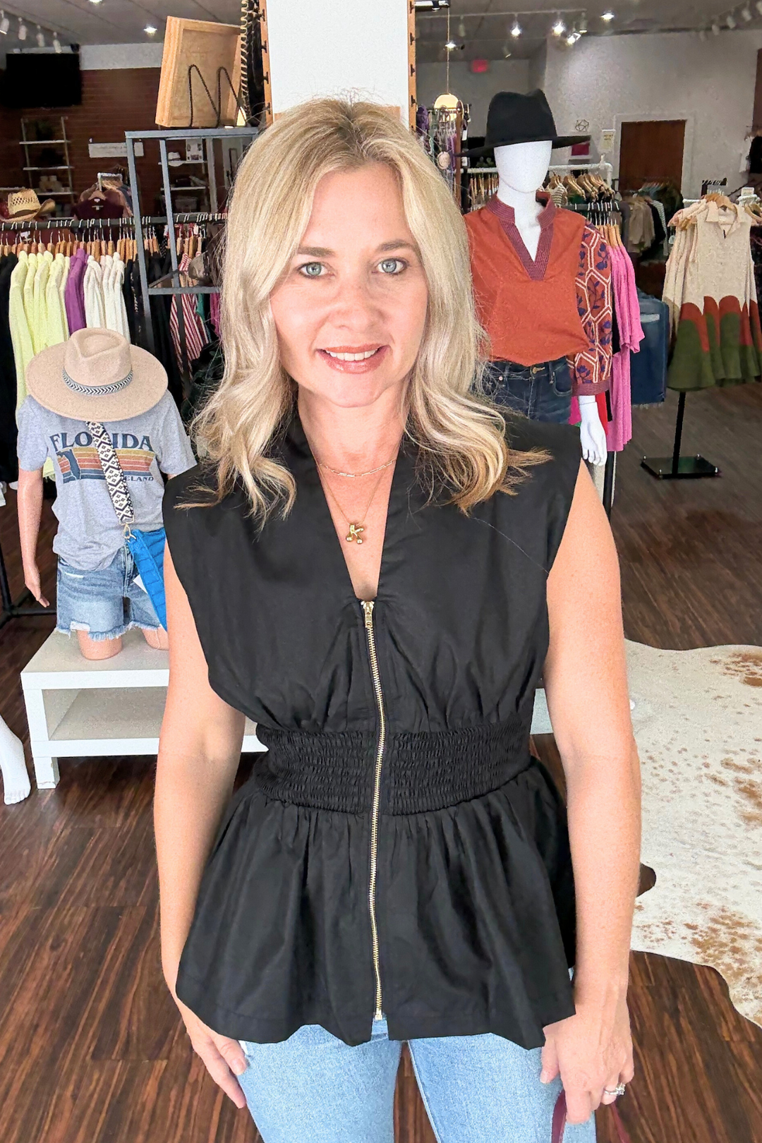 This sleeveless, woven top features a front zipper closure and combines a wide smocked waist with a flattering peplum hem for a modern silhouette. 
