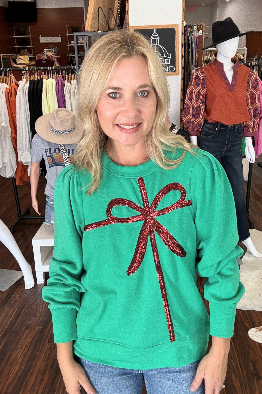 This Sequin Bow Millie Sweatshirt in vibrant kelly green features a cropped length and full-volume sleeves for a trendy silhouette. The relaxed fit and crew neckline make it easy to wear, while the striking red sequin bow across the front adds a playful, holiday touch to your casual wardrobe. 