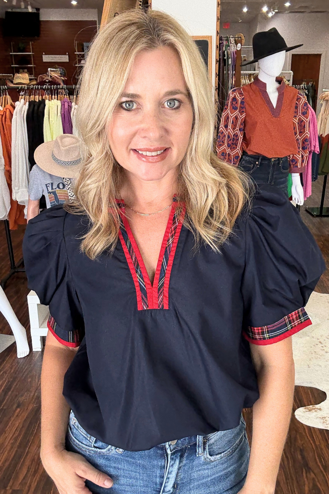 This lightweight woven top features short, pleated puff sleeves and a striking plaid contrast V-neck band for a modern edge. 