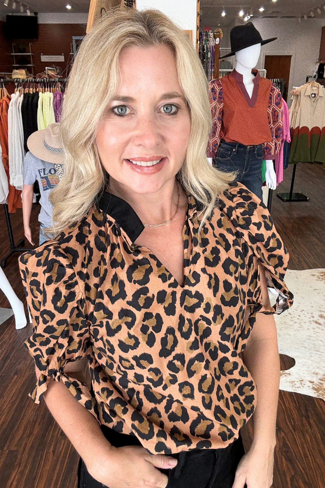 This modern short sleeve top features a bold cheetah print body accented by a striking black ruffle collar. The v-neck design adds a flattering touch, while delicate bow ties at the sleeves bring a subtle, stylish detail. 